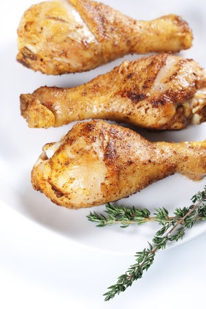 Roasted chicken legs with thyme on a plateの写真素材