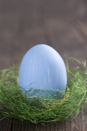 Blue easter egg in nest on wooden background の写真素材