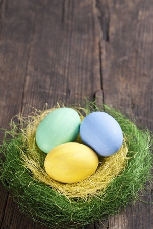 Colorful easter eggs in nest on wooden background の写真素材