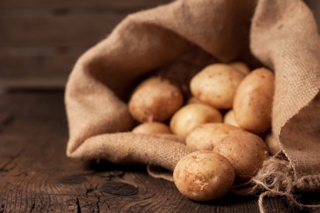 Harvest potatoes in burlap sack on rustic background Harvest potatoes in burlap sack on rustic background