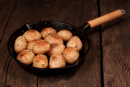 Roasted potatoes with sea salt and herbs in pan on rustic table の写真素材