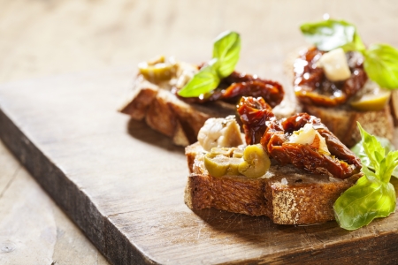 Italian appetizer bruschetta with olive oil, olives, sun-dried tomatoes and cheese.の写真素材