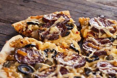 Sliced tasty salami pizza on rustic backgroundの写真素材