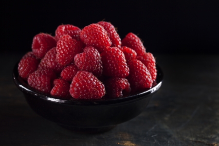 Bowl of fresh raspberry on dark background