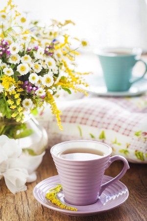 Tea and beautiful wildflowers on wooden backgroundの写真素材