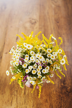 Wildflowers bouquet in glass vase on wooden backgroundの写真素材