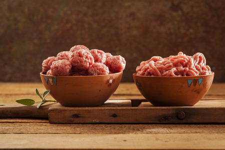 Raw meatballs in bowl with ingredients on wooden backgroundの写真素材