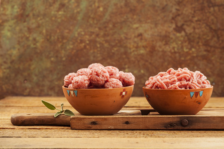 Raw meatballs in bowl with ingredients on wooden backgroundの写真素材