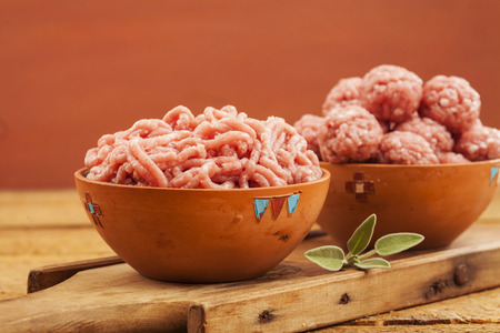 Raw meatballs in bowl with ingredients on wooden backgroundの写真素材