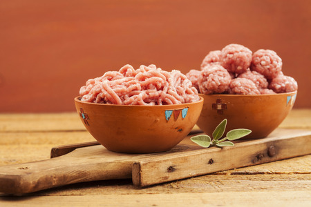 Raw meatballs in bowl with ingredients on wooden backgroundの写真素材