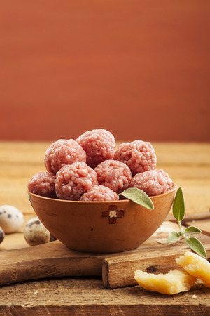 Raw meatballs in bowl with ingredients on wooden backgroundの写真素材