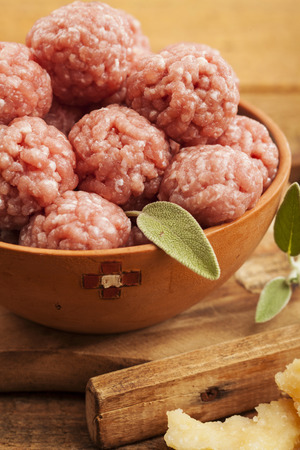 Raw meatballs in bowl with ingredients on wooden backgroundの写真素材