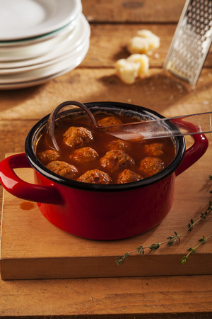 Meatballs closeup in a red casserole on wooden backgroundの写真素材