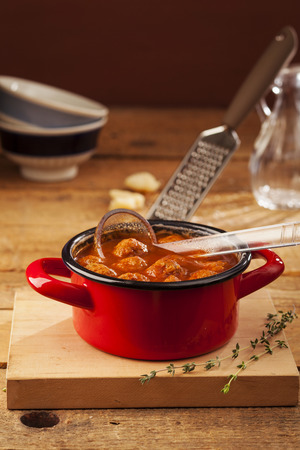Meatballs closeup in a red casserole on wooden backgroundの写真素材