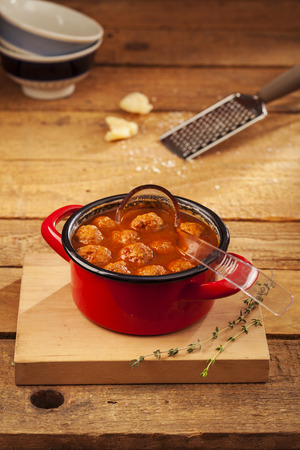 Meatballs closeup in a red casserole on wooden backgroundの写真素材