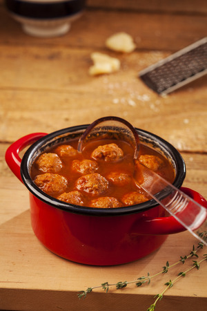 Meatballs closeup in a red casserole on wooden backgroundの写真素材