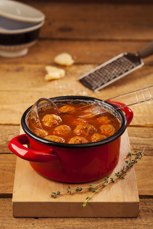 Meatballs closeup in a red casserole on wooden backgroundの写真素材