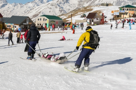 Two members of a ski patrol helping an injured skier down the mountainのeditorial素材