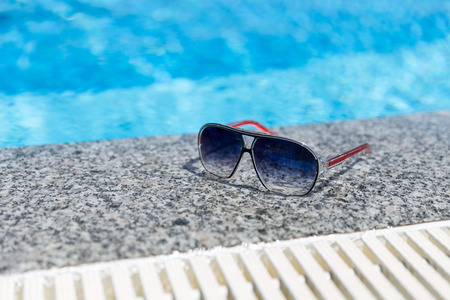 Sunglasses laying on the edge oÐ° a swimming poolの写真素材
