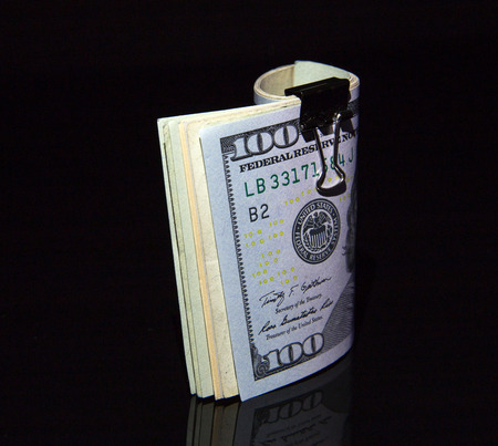 Ddollar bills rolled up with clip on black background