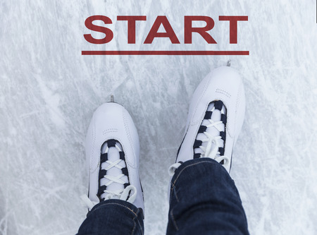 Legs of ice skater with start sign on the ice rink, view from above