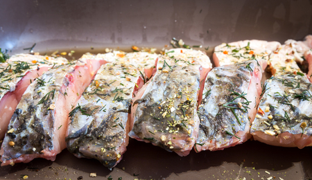 Raw fish on baking tray before cooking, blanc amour with herbs