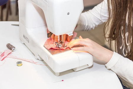 Little girl using sewing machine to make crafts
