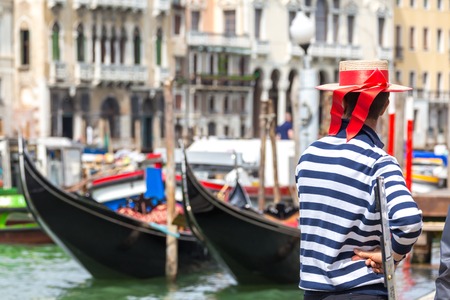 Gondolier standing next to gondola waiting for a client in Venice Italyの写真素材