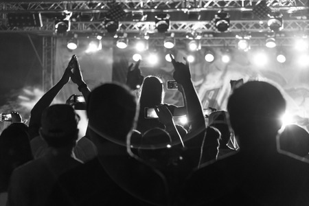 Black and White Silhouette of People in Crowd at a Music Festival. Concert with backlit standing dancing peopleの写真素材