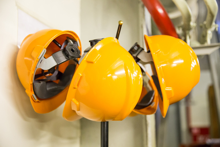 Yellow hard hat safety wear helmet hanging on coat rack at construction siteの写真素材