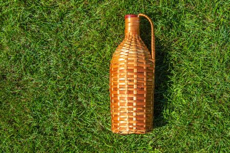 Rattan wine bottle laying on green grass lawn , pic nic conceptの写真素材