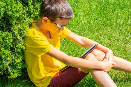 Boy studing in a park reading information on a tableの写真素材