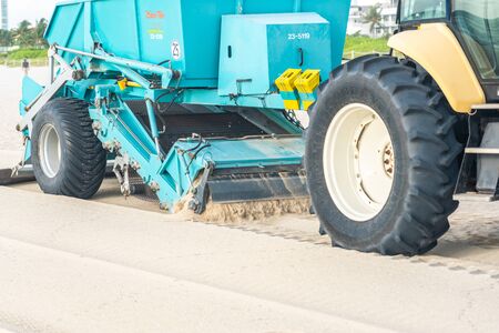 Miami, USA - September 11, 2019: Tractor cleaning sand in South beach in Miami