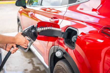 Woman with fuel pistol and red car