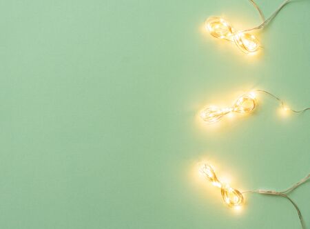 Christmas lights on light green background, flat lay with holiday garlandの写真素材