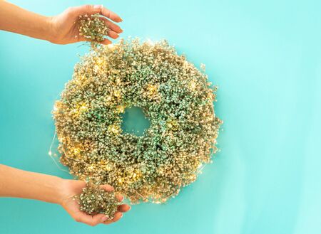 Female hands decorating christmas wreath with garland, top viewの写真素材