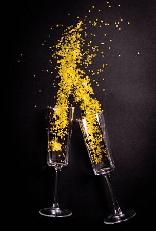 Two Glasses with yellow tinsel on black background, flat lay top viewの写真素材