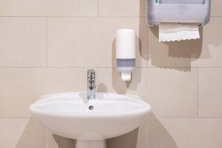 Sink next to soap dispenser pump and paper towel dispenserの写真素材