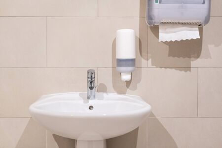 Sink next to soap dispenser pump and paper towel dispenser