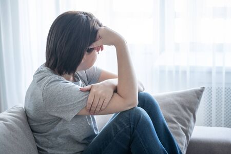 sadness girl sits on the sofa at homeの写真素材