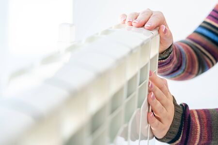 Woman touching warm radiator with both hands