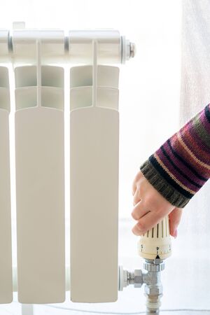 Radiator adjustment closeup. Female hand adjusting radiator temperatureの写真素材