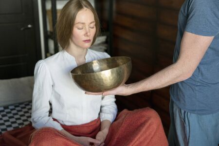 Man holding tibetan singing bowls in sound therapy in spa centerの写真素材