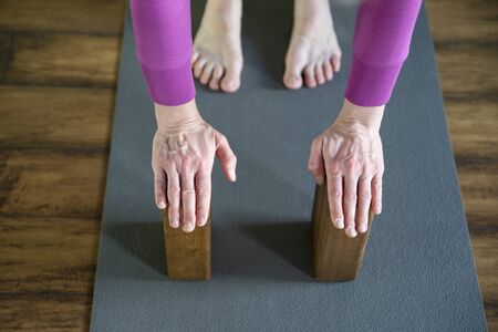 Women practicing yoga therapy, stretching in down dog using blocks and the wall, downward facing...