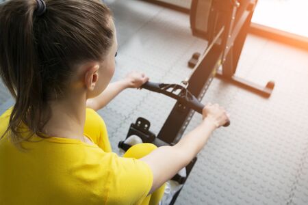 Close up view of female fitness instructor uses a rowing machine