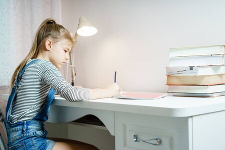 Teenage girl doing homework at table at home preparing for school test