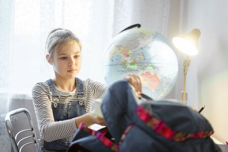 Preteen girl packing stuff in backpack at the table for school after finishing homeworkの写真素材