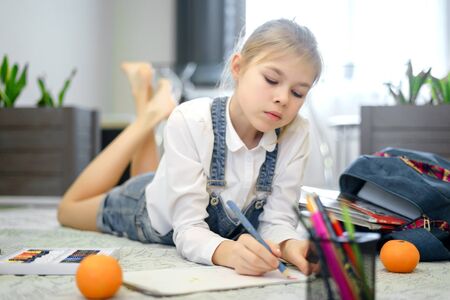 Cute little girl is drawing on a floor in living roomの写真素材