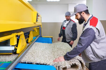 Laundry worker in the process of working on automatic machine for carpet washing in dry cleaningの写真素材