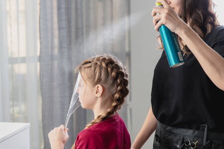 Hair stylist weaves braid to preteen girl in beauty salonの写真素材